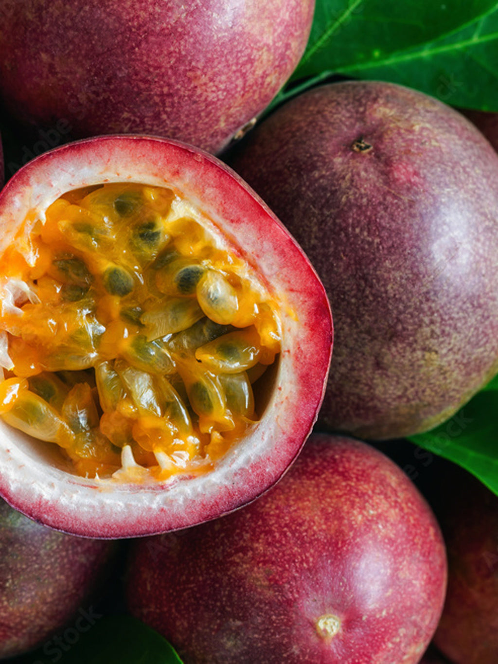 Passion fruit with a cut open showing its juicy interior.